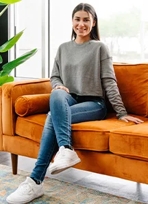Woman sitting on an orange couch.